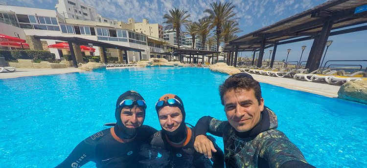 Three freedivers in an outdoor pool ready to train STA static apnea and dynamic apnea