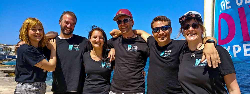 six freedivers with the apnea total malta tshirt posing on camera with the blue at the background