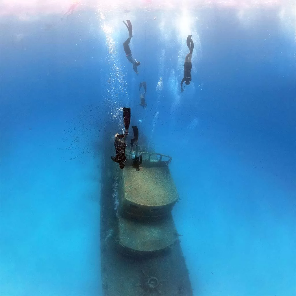 a group of freedivers descending to the top of a wreck in malta during one of our boat trips in comino