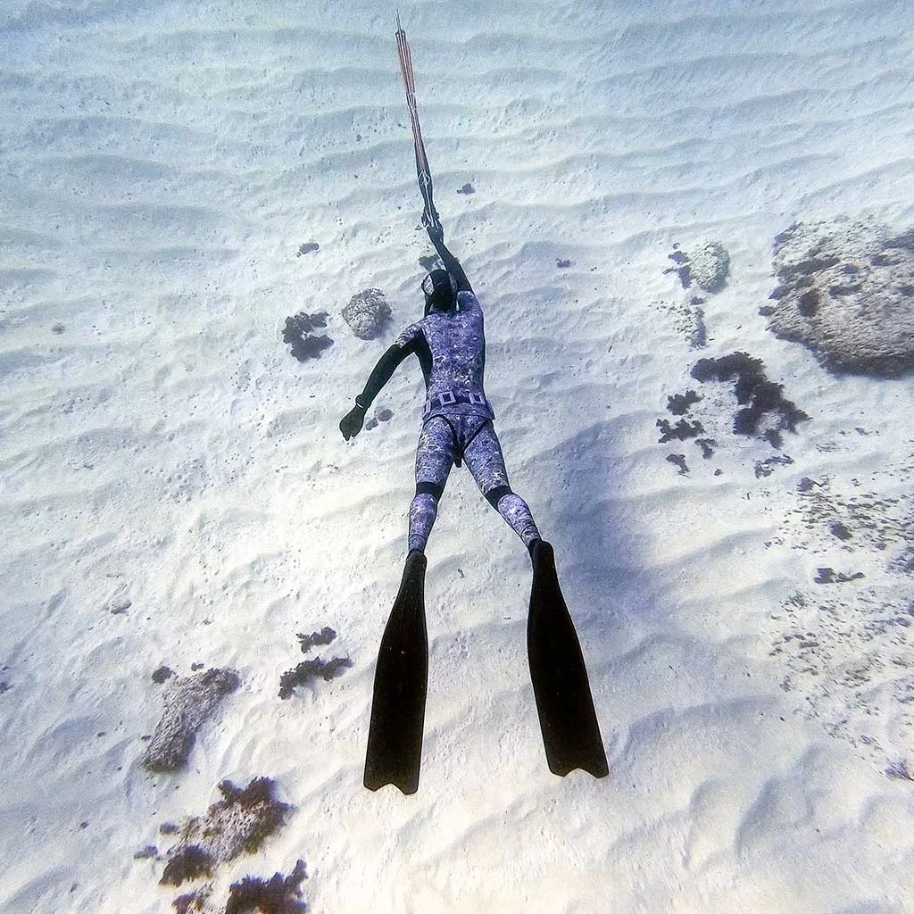 Spearfisher in Malta aiming with his speargun in a sandy bottom