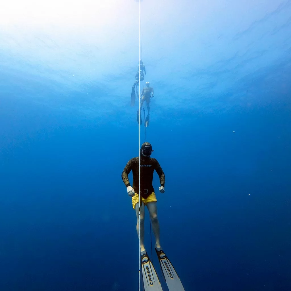 Freediving training sessions in Malta with one freediver ascending the line and another two freedivers at the background doing each other safeties