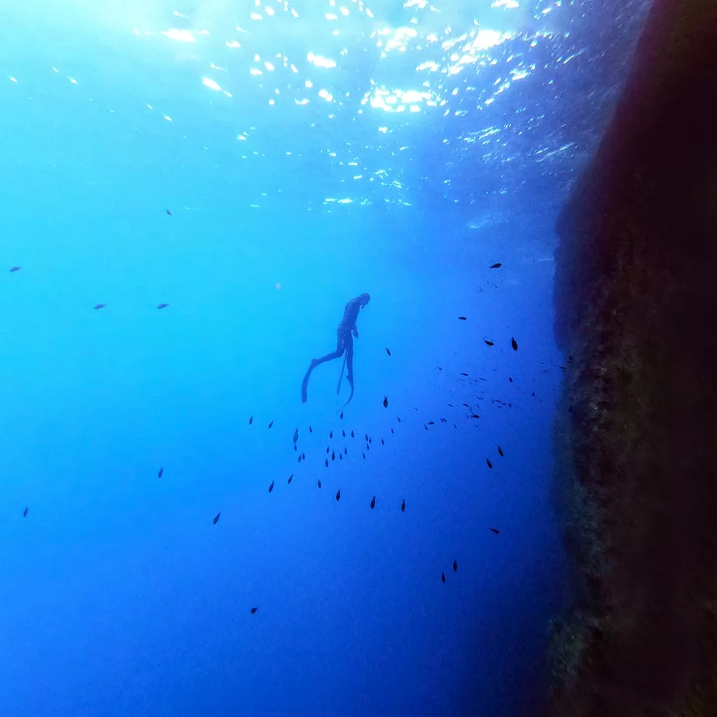 silhouette of an advanced spearfisher in malta ascending with his speargun close to a drop off